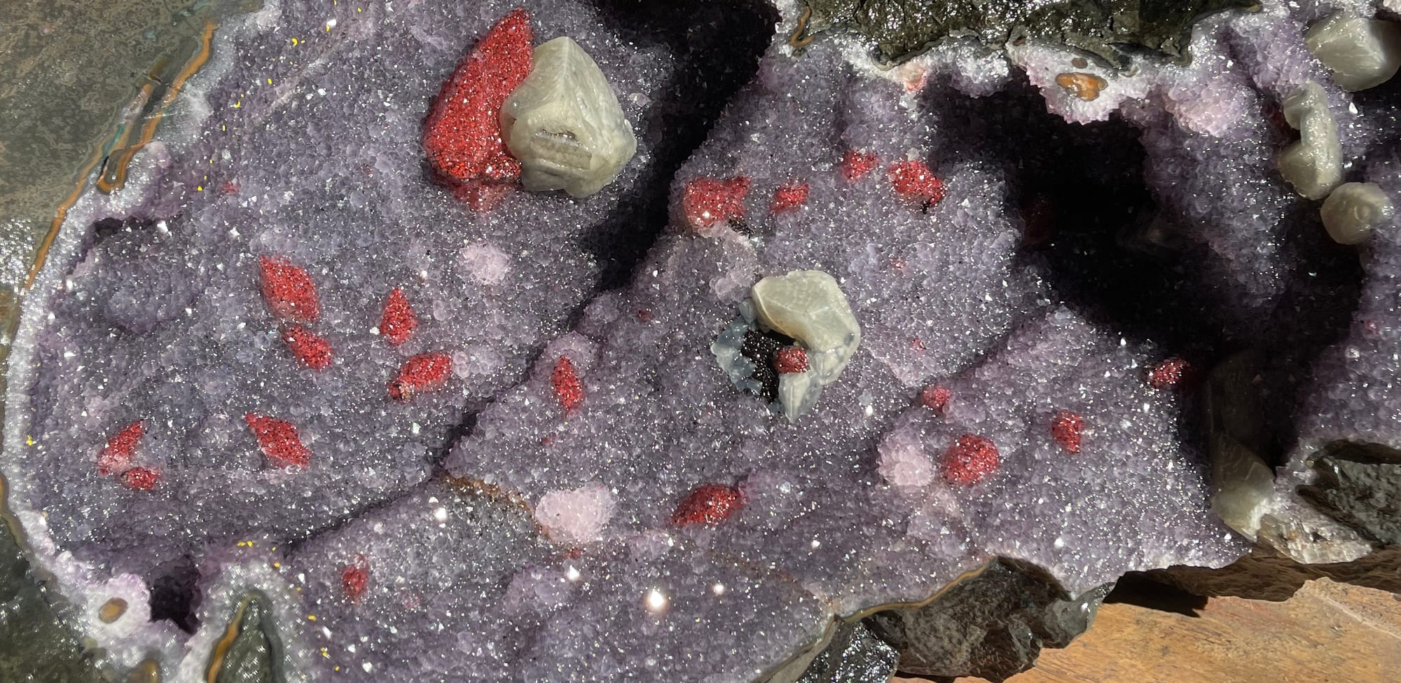 Laja de geoda de más de un metro, abierta, con cristales de calcita roja; una mano y una cinta métrica dan la escala