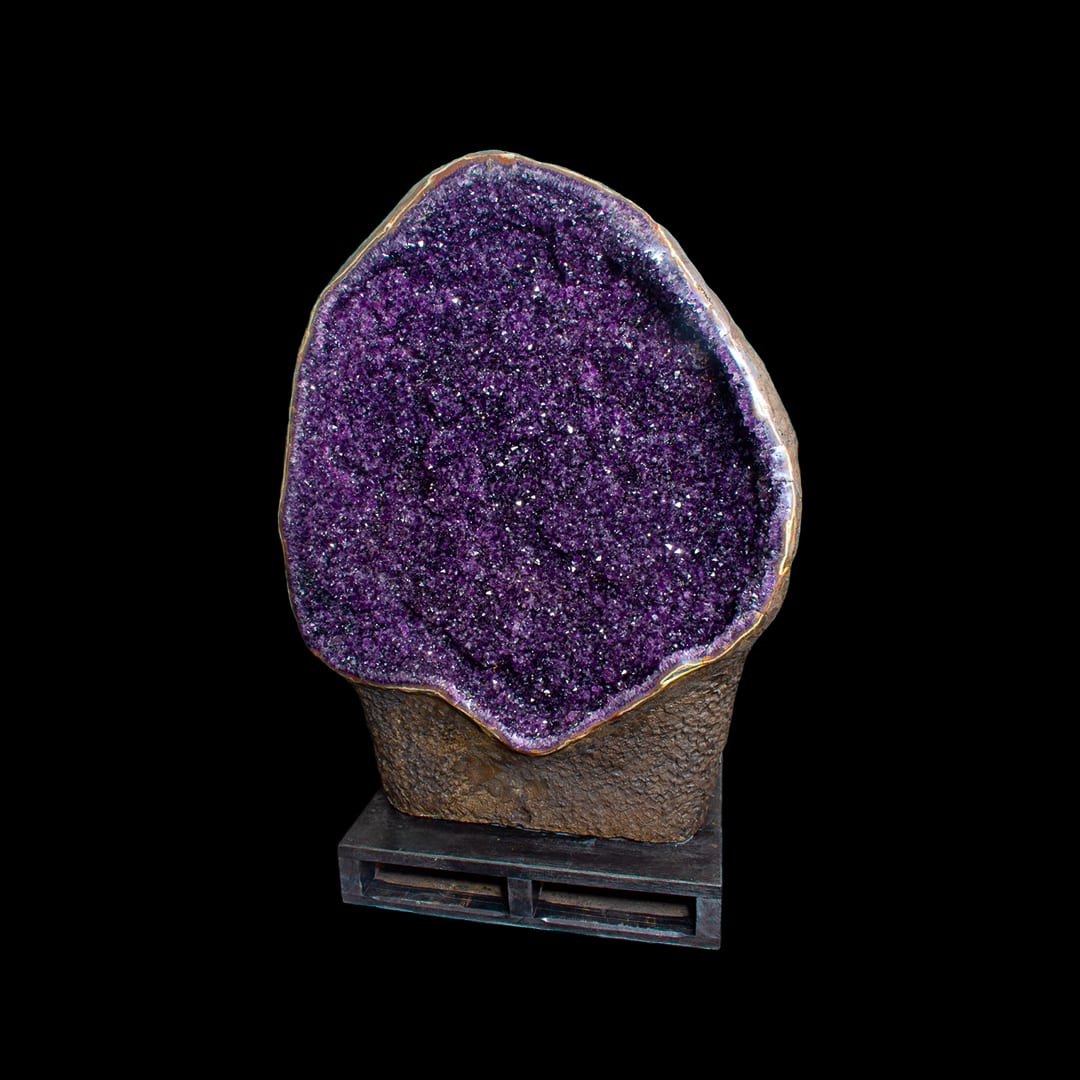 An open amethyst geode on its own rock, on a metal base