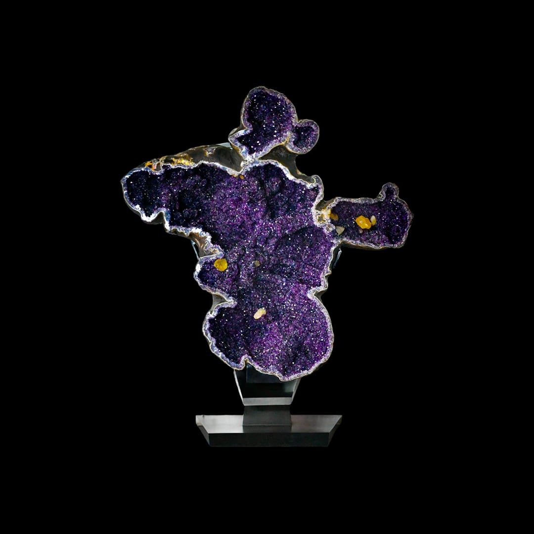 An amethyst plate with an intricate outline, on a metal stand
